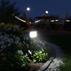 Solar spotlight in a flower bed with a lit patio table beyond