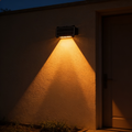 Aurevia Halo solar wall light casting twin warm beams up and down a rendered exterior wall at night