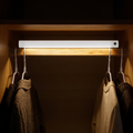 Aurevia Slip cabinet light bar mounted in a wardrobe, lighting a rail of hanging clothes