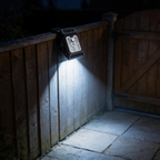 Aurevia Clasp solar motion light clipped to a garden fence, lighting the path by a back gate at night