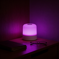 Aurevia Prism 16 colour table lamp glowing violet on a bedside table at night