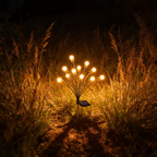 Aurevia Spark solar firefly lights glowing among ornamental grasses in a garden border at night