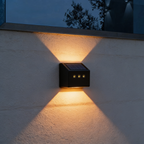 Aurevia Ledge solar fence light casting warm light up and down a rendered garden wall at night