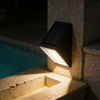 Close view of a solar step light mounted on a stone step, solar panel on top and trapezoid lens washing light downwards