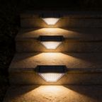 Three solar step lights fixed down a flight of stone garden steps, each washing warm light onto its own tread at night