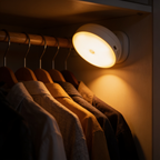 Motion sensor night light mounted inside a wardrobe, warm light falling across hanging shirts and the rail