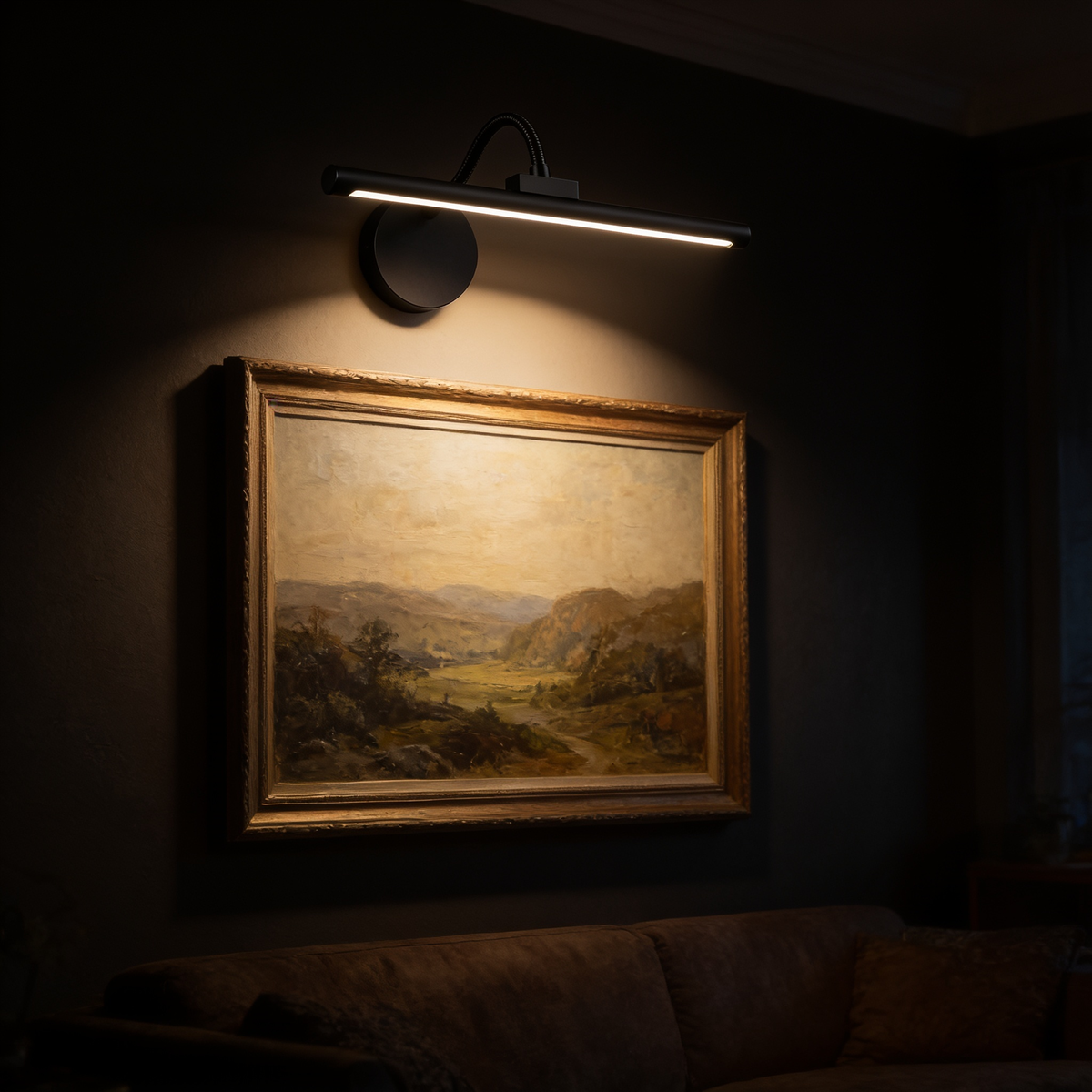 The Pivot cordless picture light mounted above a framed landscape painting in a dark room, washing warm light down over the canvas
