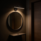 The Pivot picture light above a round hallway mirror, lighting the glass and the console table below