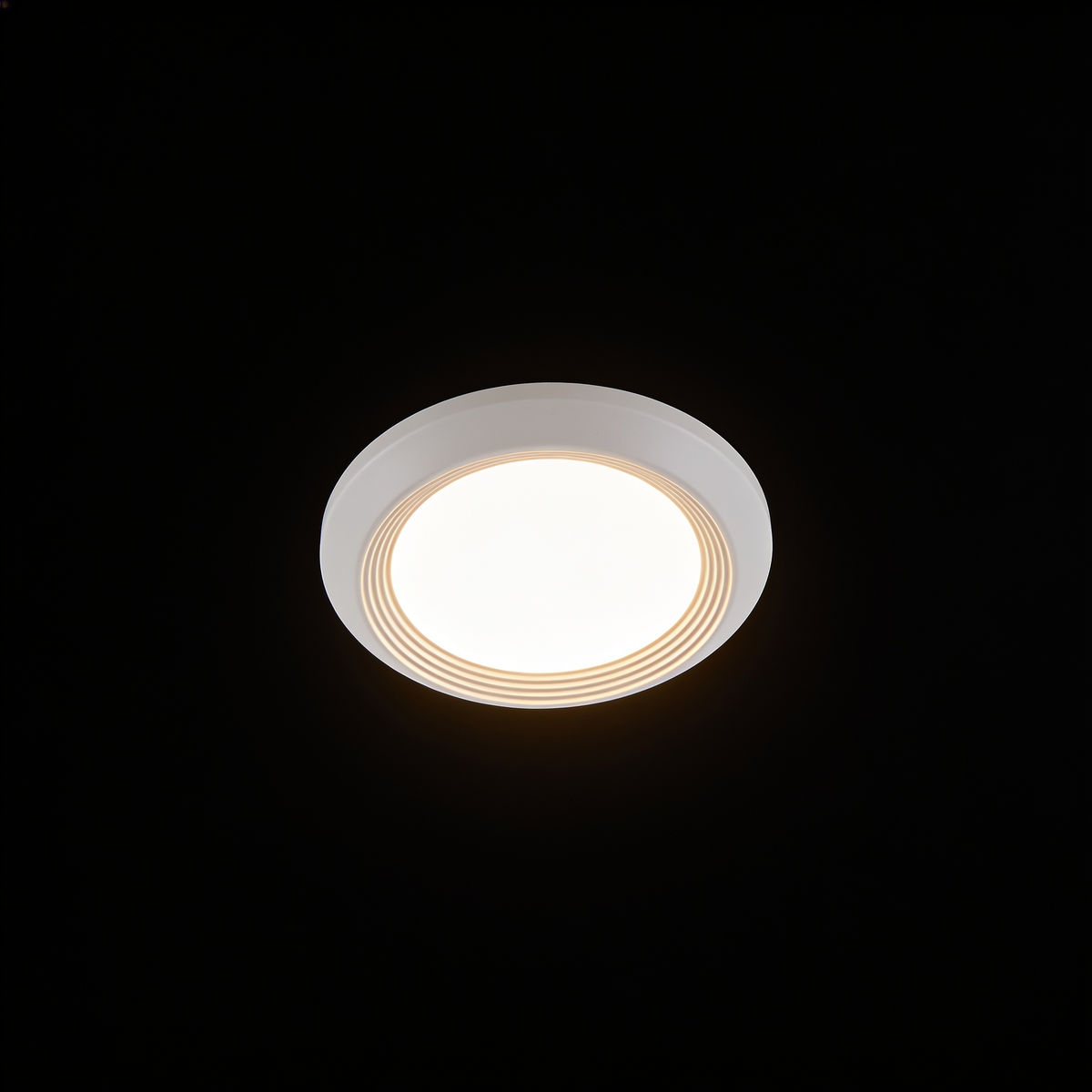 The Orbit ceiling light on a black studio background, showing its shallow white disc and stepped rim